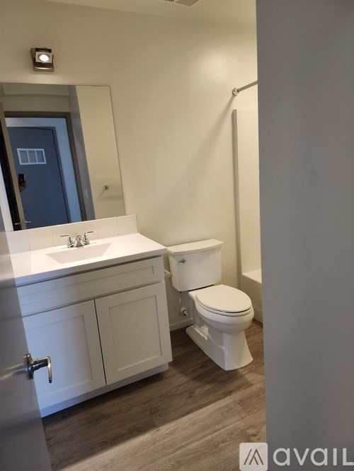 A bathroom with a toilet, sink, and mirror.