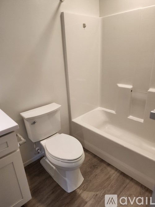 A white toilet in a bathroom with a white tub.