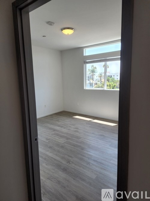 A room with a window and a wooden floor.