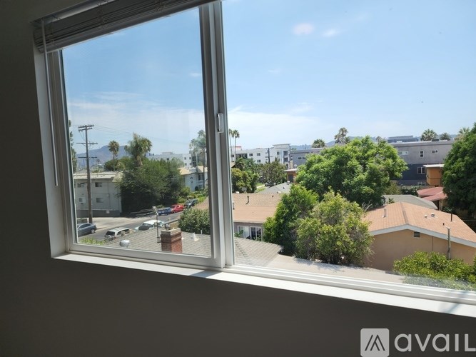 A window with a view of a street with cars and houses.