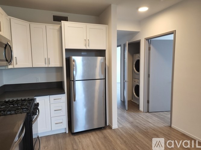 A kitchen with a stainless steel refrigerator and a black stove top.