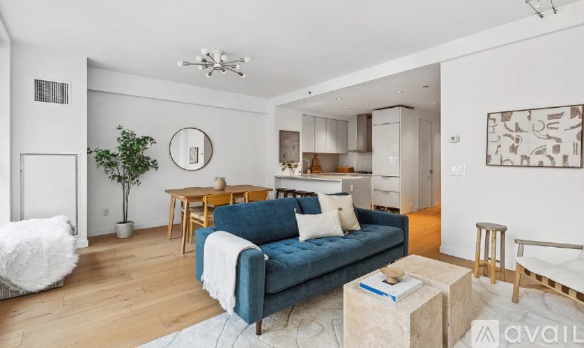 A living room with a blue couch and a white rug.