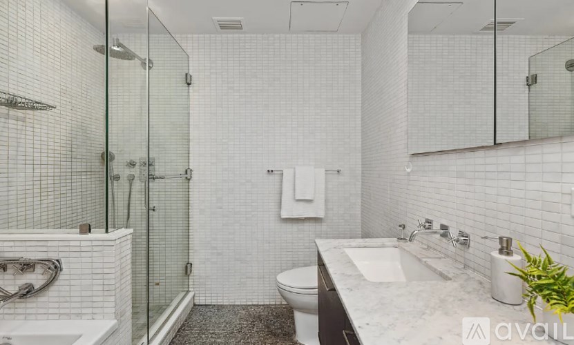 A bathroom with a white tiled shower and a glass door.