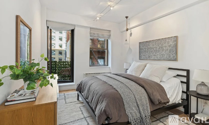 A bedroom with a large bed and a window overlooking a cityscape.