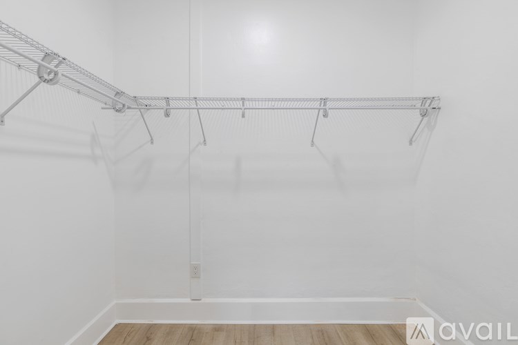 A white wall with a clothes rack and a wooden floor.