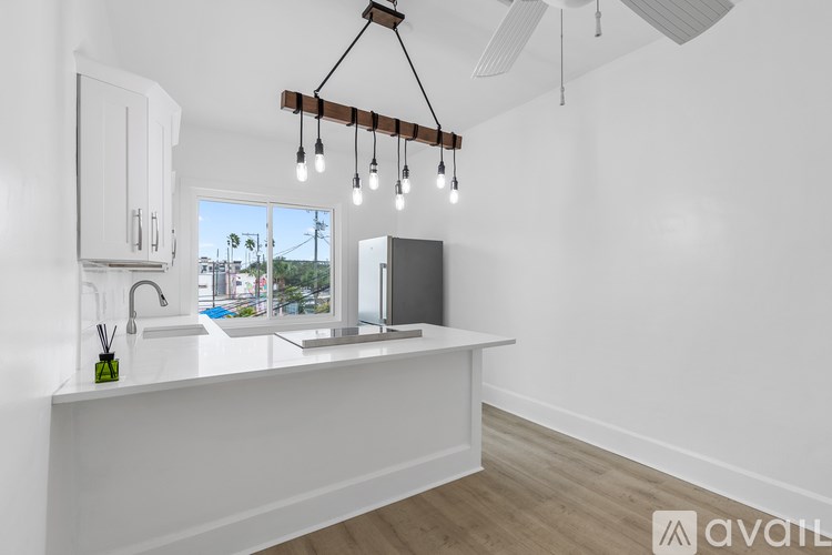 A kitchen with white cabinets and a wooden light fixture.