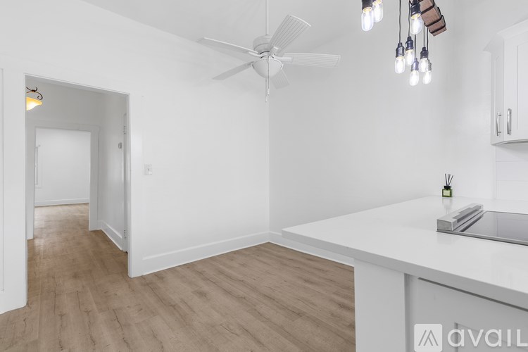 A white room with a fan and a table with a laptop on it.