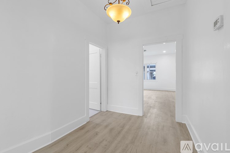A room with a wooden floor and a hanging light fixture.