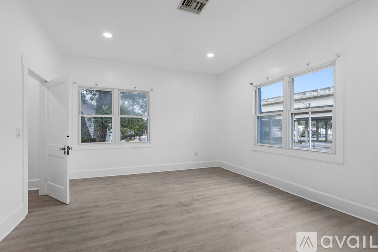 A room with a door, two windows, and a wooden floor.