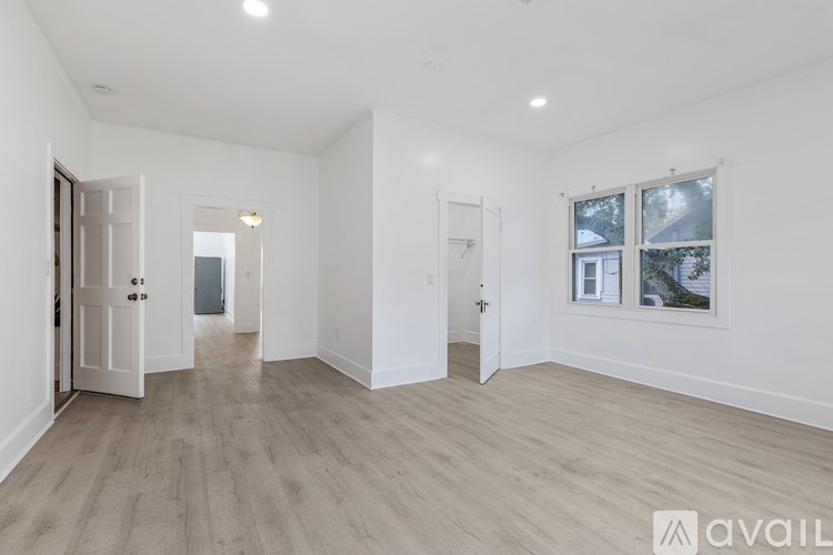 A spacious room with wooden flooring and white walls.