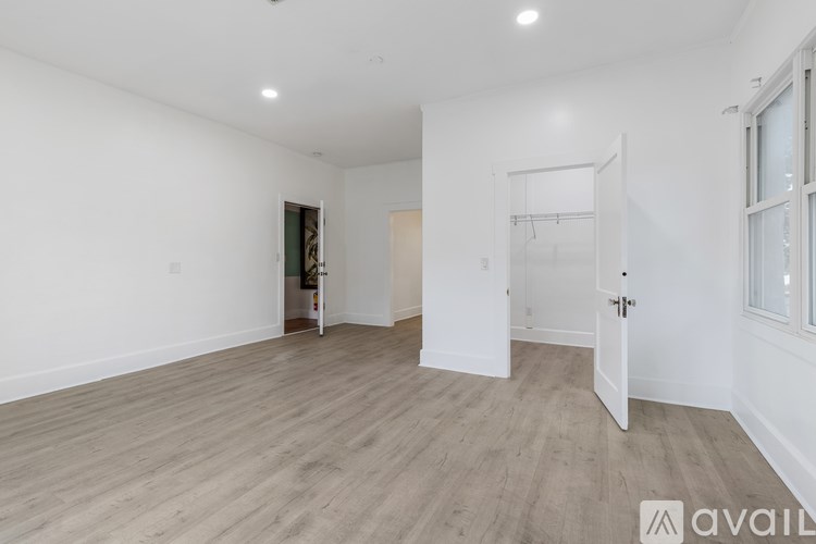 A spacious room with wooden flooring and white walls.