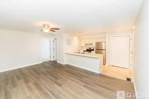 A spacious room with wooden flooring and a ceiling fan.
