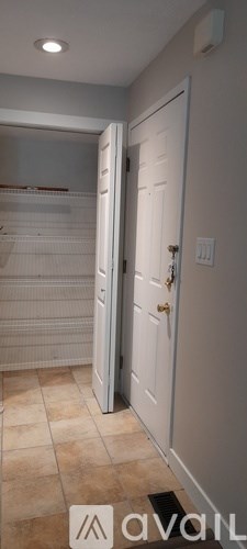 A white door is open to a hallway with a tiled floor.