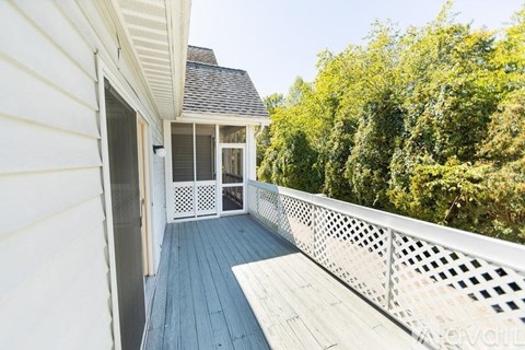A white house with a deck and a screened in porch.