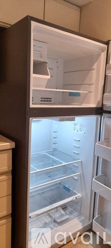 A refrigerator with the door open showing the empty shelves.
