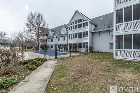 A large white house with a black fence and a playground in front.