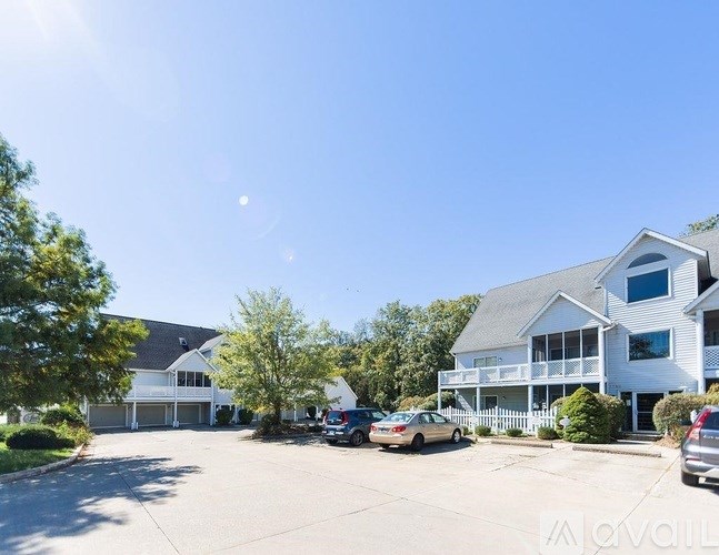 A large white house with a carport and a car parked in front.