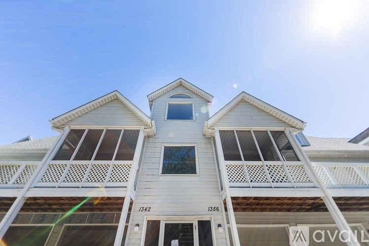 A white two-story building with a balcony on the second floor.