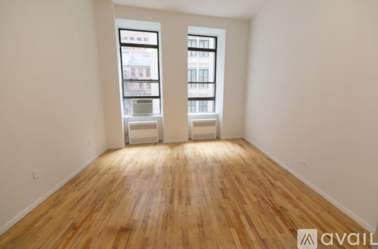 A room with wooden floors and two windows.