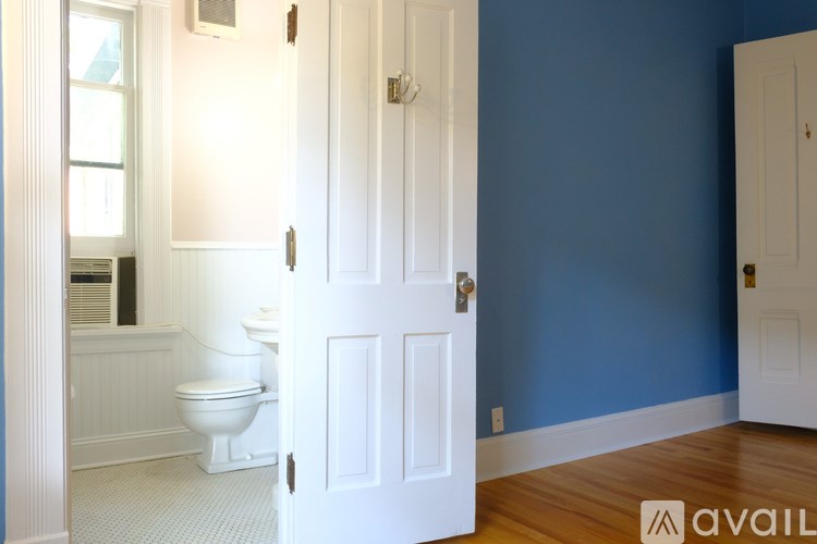 A white door is open to a bathroom with blue walls.