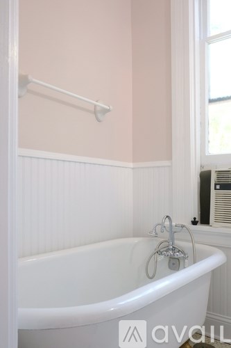 A white bathtub with a shower head attached to the wall.