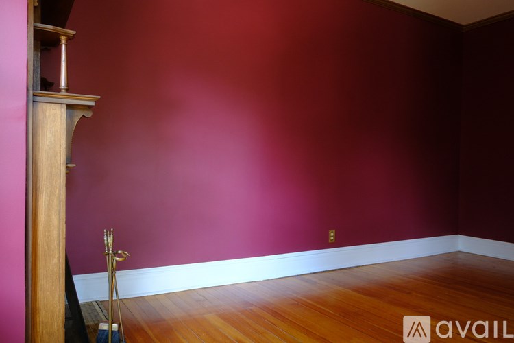 A room with a wooden floor and a pink wall.