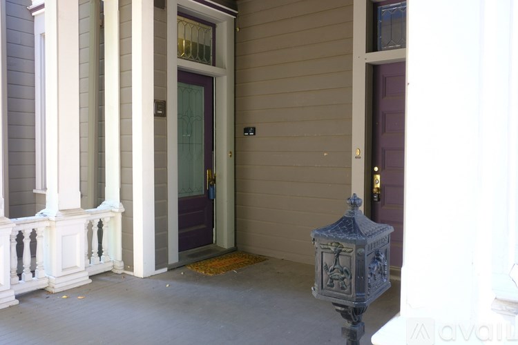 A grey lantern stands on a porch with a purple door.