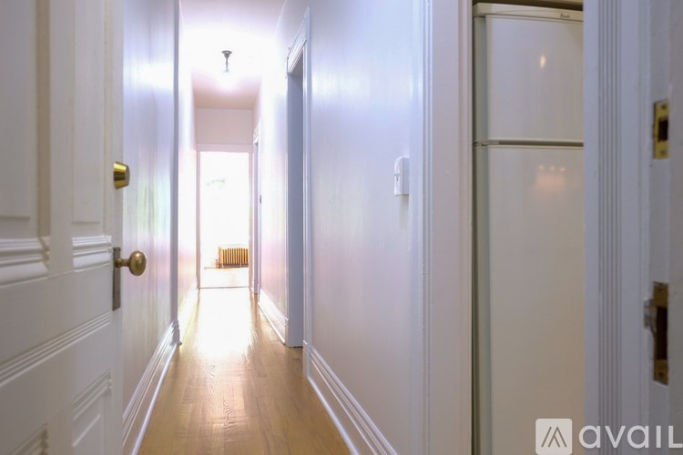 A hallway with white walls and a wooden floor.