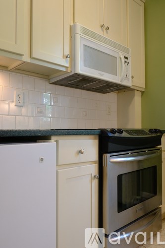 A white microwave is mounted above a stainless steel oven in a kitchen.