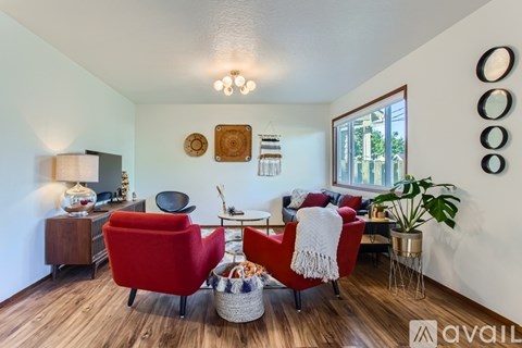 A living room with a red chair and a wooden floor.