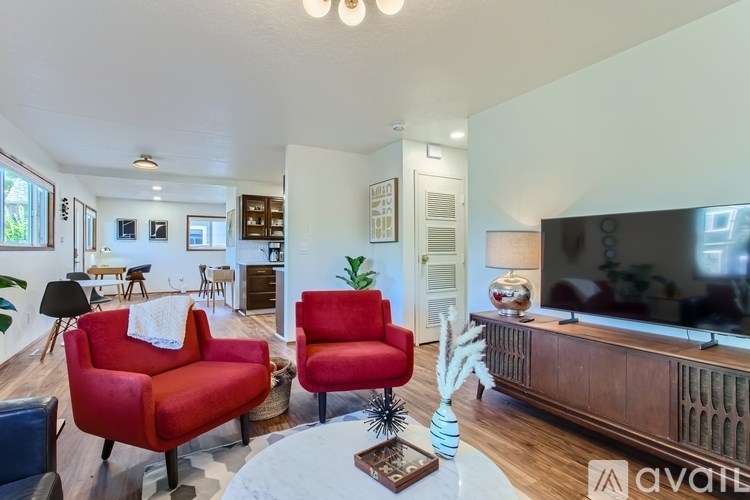 A living room with red chairs and a wooden entertainment center.