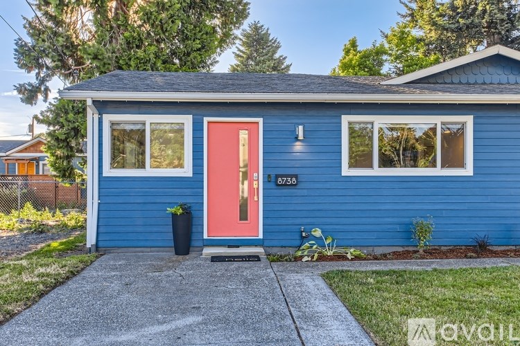 A blue house with a red door and the number 8736 on it.