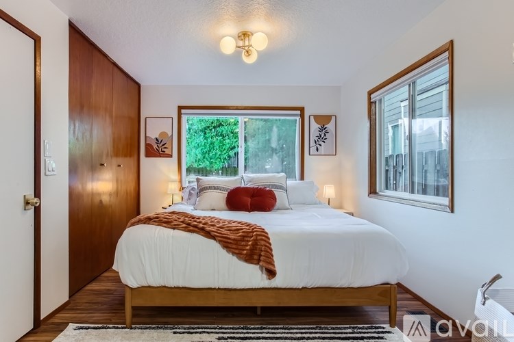 A bedroom with a bed, a window, and a rug.