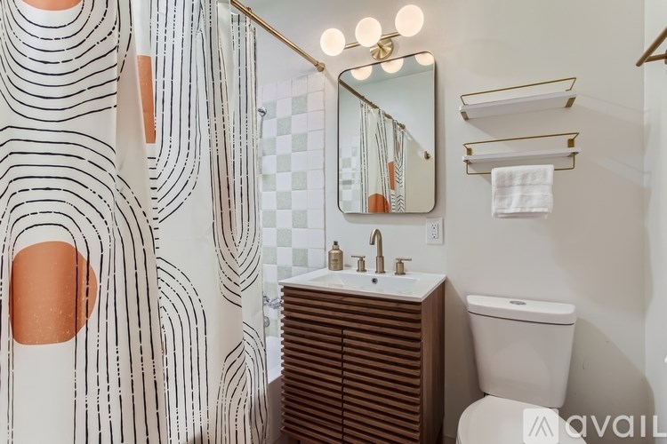 A bathroom with a white sink and a mirror with lights above it.