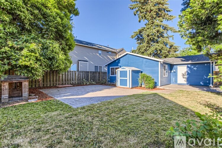 A blue house with a gravel driveway and a wooden fence.