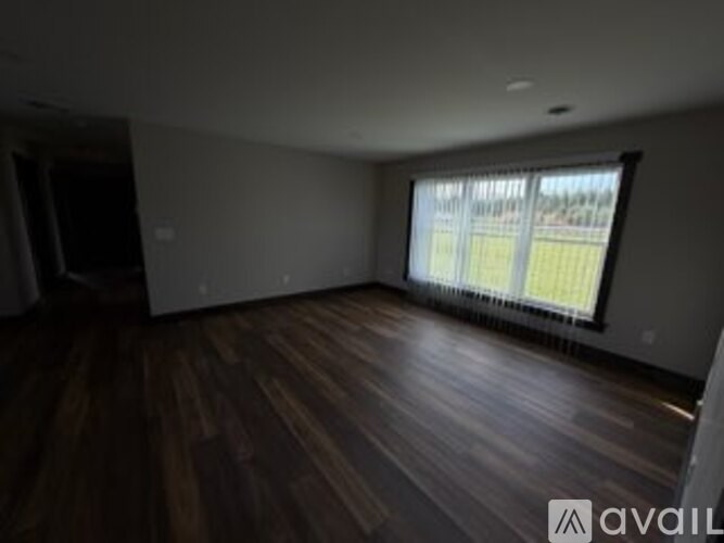 A room with wooden floors and a window with blinds.