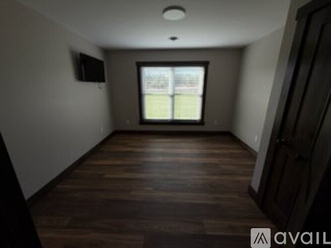A room with wooden floors and a window showing a view of a building.