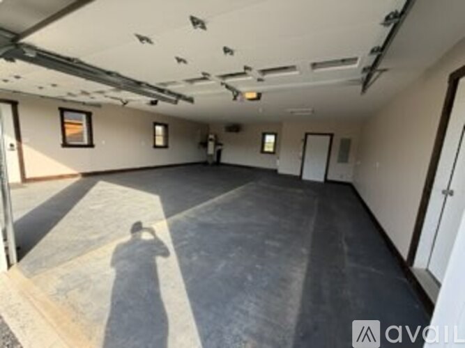 A person is taking a photo in an empty room with a concrete floor.