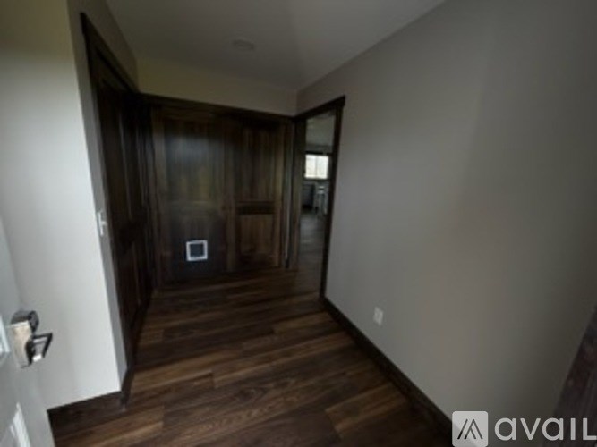 A hallway with wood floors and a white wall.