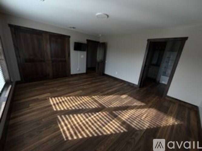 A room with wooden floors and a large window letting in sunlight.