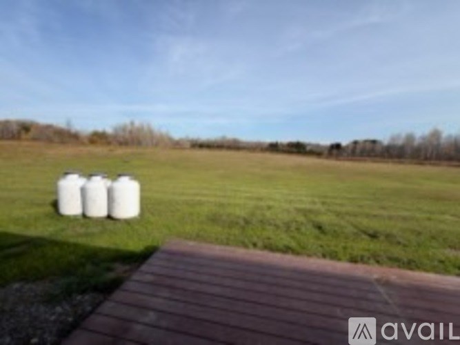 Three white barrels are placed on a grassy field.