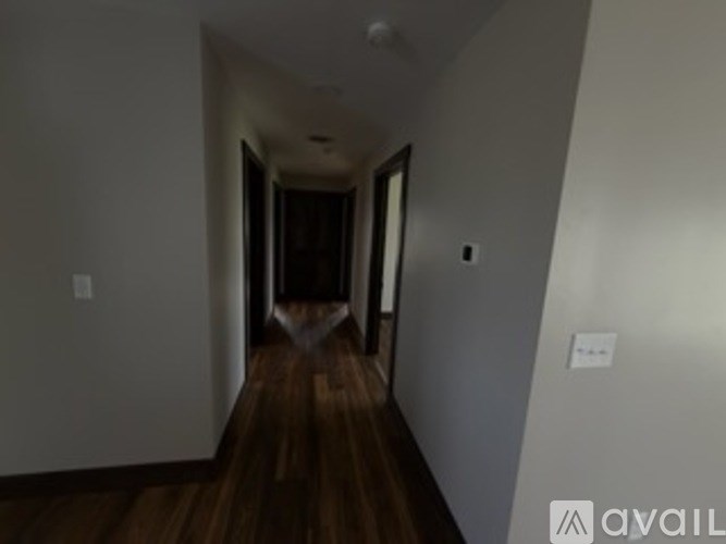 A hallway with wood floors and white walls.