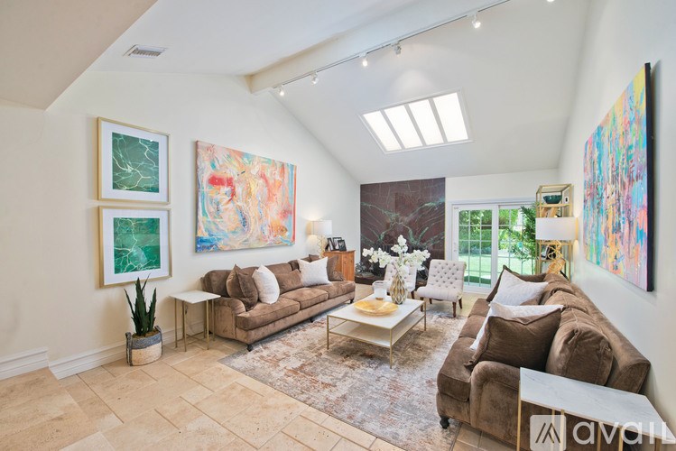A living room with a brown couch and a painting on the wall.