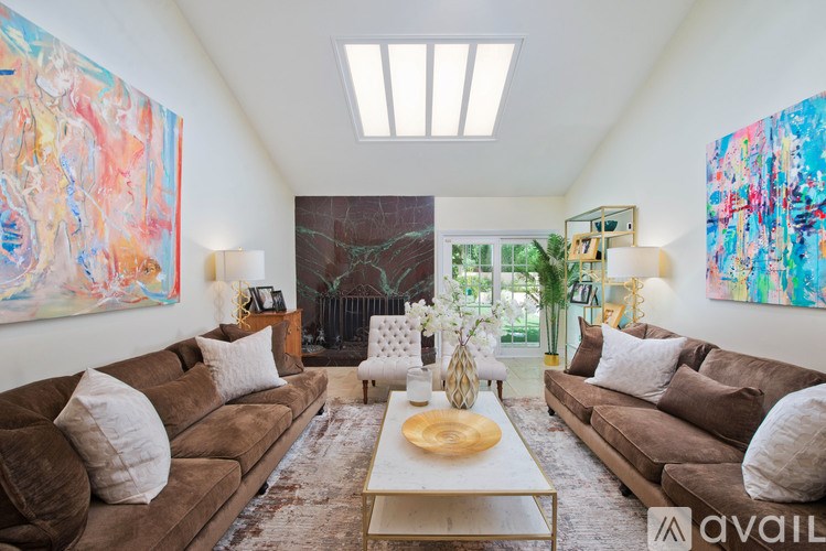 A living room with brown couches and a large painting on the wall.