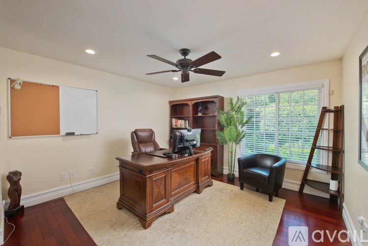 A room with a brown desk and a fan on the ceiling.