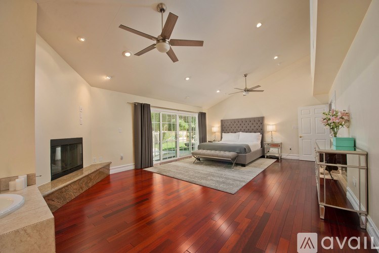 A bedroom with a bed, a fireplace, and a ceiling fan.