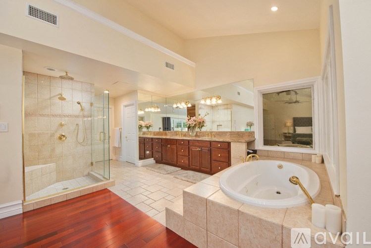 A large, luxurious bathroom with a wooden floor and a bathtub.