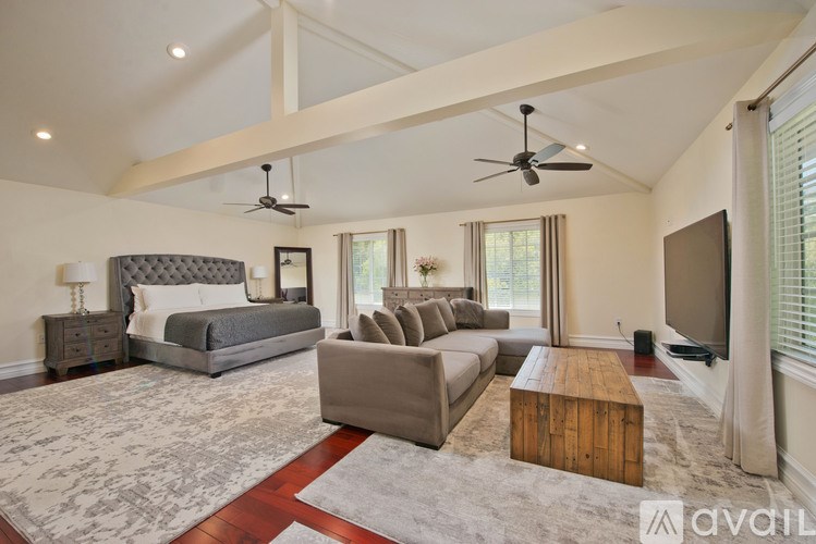 A spacious bedroom with a large bed, a couch, a coffee table, and a television.