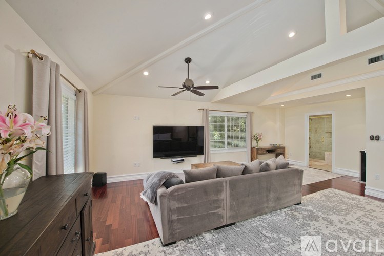 A living room with a grey couch and a flat screen TV mounted on the wall.