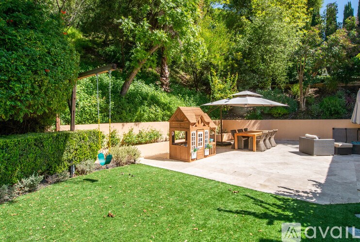 A backyard with a swing set and a small wooden playhouse.